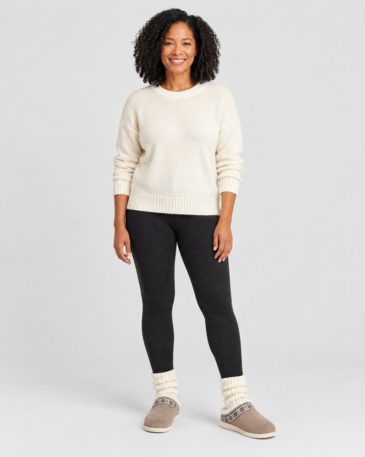 Vrouw in een ecru trui en zwarte legging met Teodora pantoffels in zacht taupe