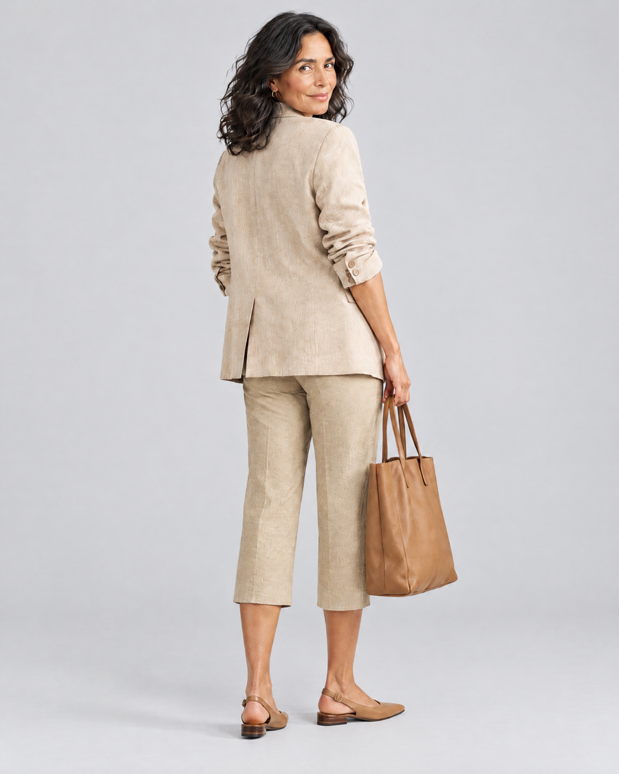 Achteraanzicht van een vrouw in de Marta capribroek in lichtkaki met een beige blazer en een bruine shopper